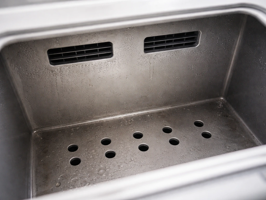 Top interior close-up of a ventilation slot and floor drainage holes in a wet nest drying housing unit.